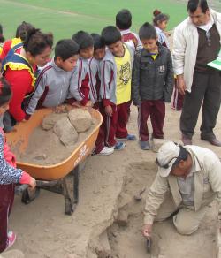 Niños observando excavación arqueológica con su profesor