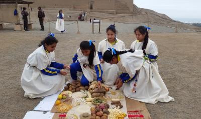 Jóvenes vestidas con réplicas de vestimenta inca realizando un pago a la tierra