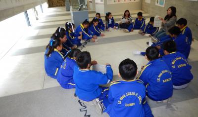 Escolares sentados en círculo recibiendo información sobre una exposición temporal