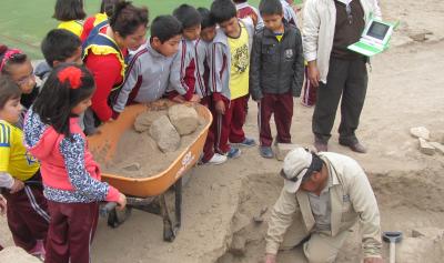 Niños observando excavación arqueológica con su profesor