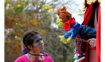 Joven con la cara pintada observando una marioneta