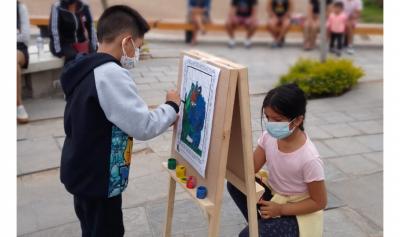 Niños pequeños pintando sobre un mini atril en la plaza del museo